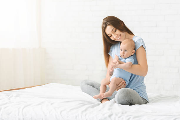 istock Mother Lovingly Holds Baby in Cozy Indoor Setting During Morning Sunlight 2194229601