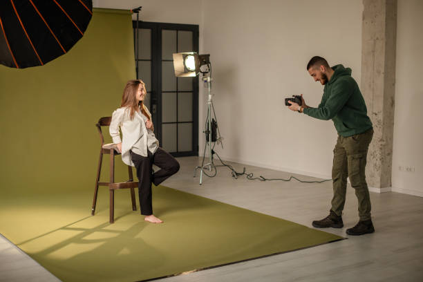 Standing photographer captures model on green backdrop
