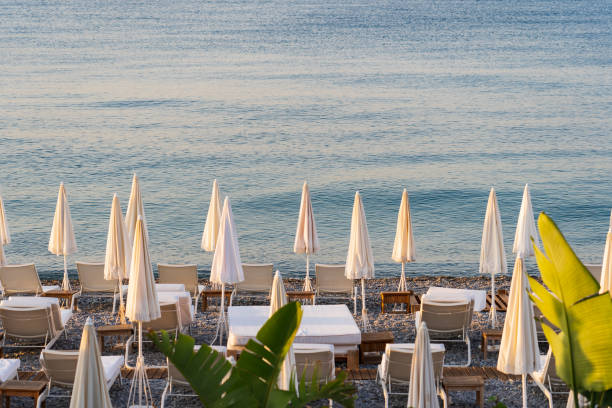 Nice awakens: the city beach with empty sunbeds and folded umbrellas meets the dawn.