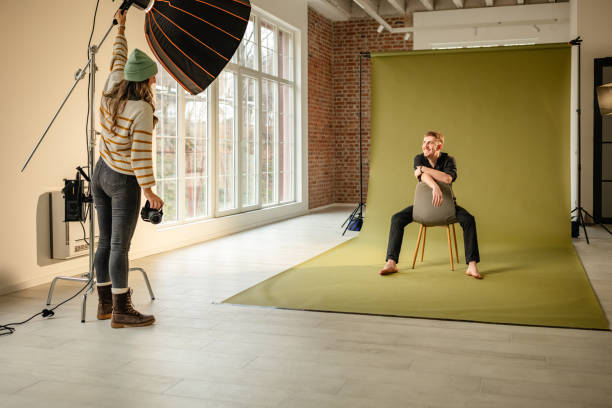 istock Woman adjusts studio light for seated subject photo. 2194231309