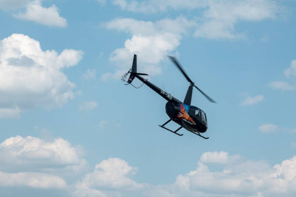 Kharkiv, Ukraine - August 29, 2021: Helicopter Robinson R44 Raven II flying in blue sky with clouds on airshow