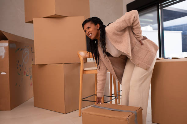 istock Woman Struggling with Back Pain While Moving Boxes. 2194231685