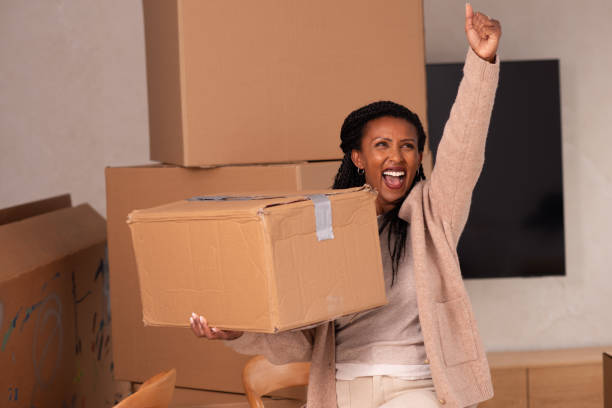 istock Celebratory Woman Holding a Box During Moving Day. 2194231743