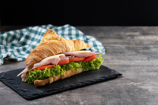 istock Croissant with ham, cheese and vegetables on wooden table 2194233365