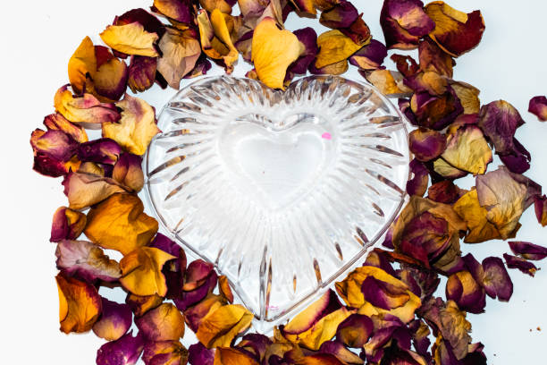 From above view of yellow and pink rose petals combined together around a glass bowl.