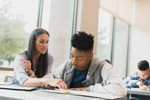 istock Teacher assisting high school student with homework, indoors 2194233451
