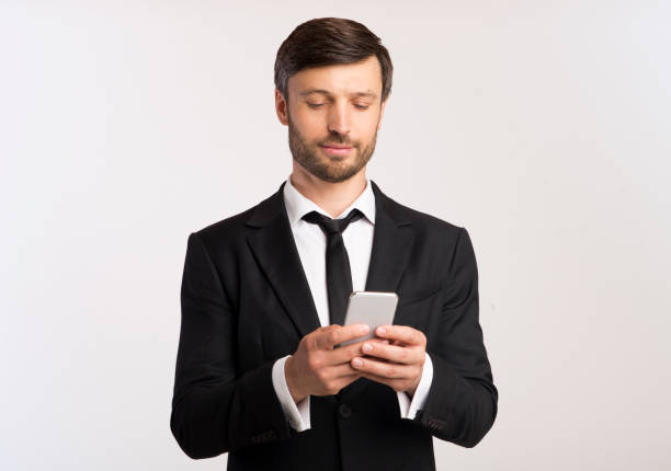 istock Man in Formal Attire Checking Smartphone While Standing With Neutral Background 2194236587