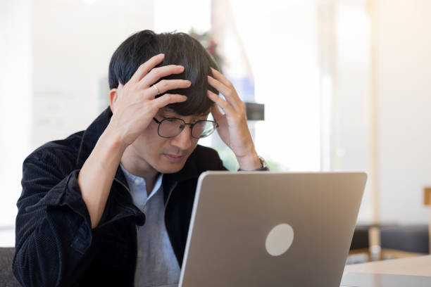 istock close up young employee asian man headache and stress about marketing project while working in office or have issues on task for healthcare and lifestyle concept 2194238574
