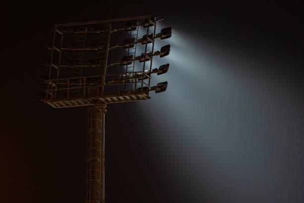 Casting powerful beams of light into the dark night sky, stadium lights create a dramatic and atmospheric scene, illuminating the empty arena with an intense glow