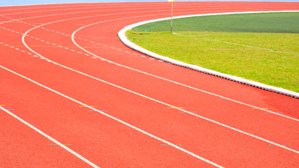 istock Red synthetic running tracks background with white curve lines pattern and green field in athletic outdoors soccer stadium 2194242815
