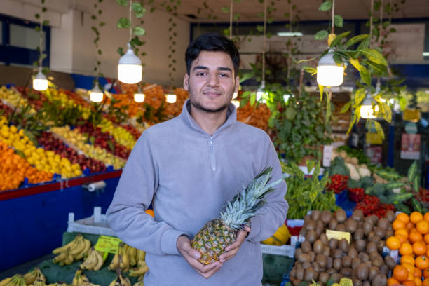 istock Young greengrocer holding pineapple in fruit and vegetable shop 2194243377