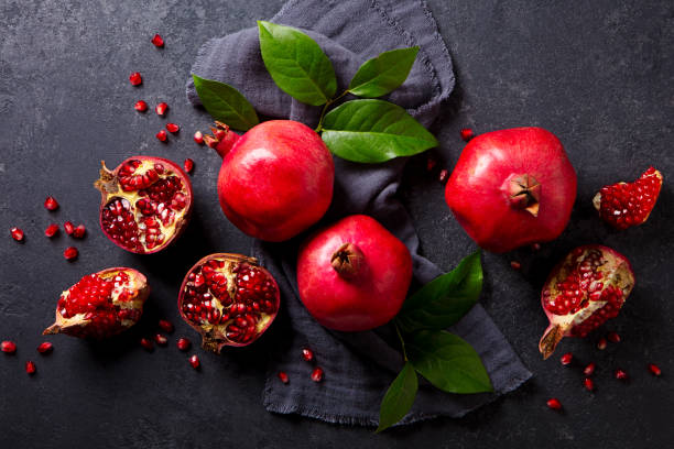 istock Fresh pomegranates with green leaves on the table. Dark grey background. Close up. Top view. 2194243620