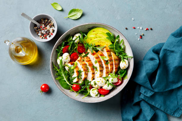istock Warm grilled chicken salad with avocado and mozzarella cheese. Close up. Top view. 2194244098