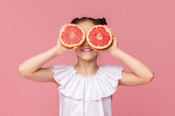 istock Cute girl holding grapefruit slices near her eyes 2194244519