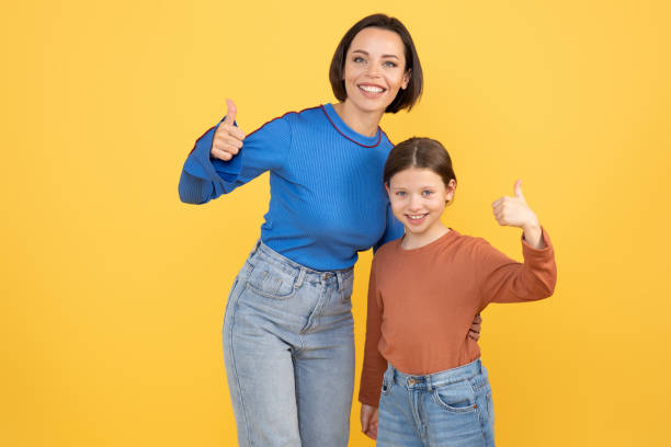 istock Mother and daughter share a joyful moment with thumbs up in a bright setting 2194244637