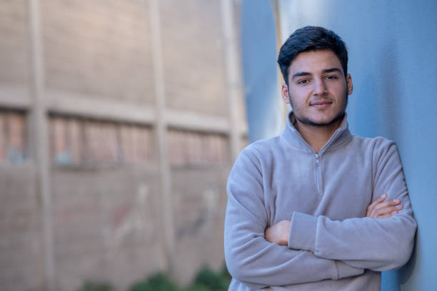 istock Young man leaning against blue wall with folded arms 2194244990