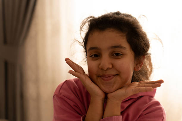 Smiling latin girl sitting in her cozy bedroom, enjoying playful moments inside her pink tent, radiating happiness and joy