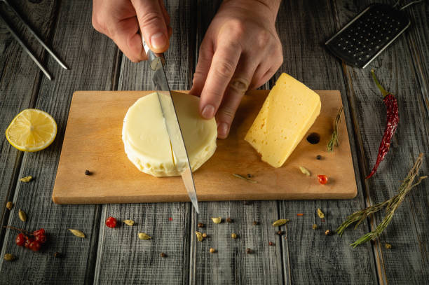 istock Hands expertly cut a creamy cheese while surrounded by herbs, spices, and a lemon on a weathered wooden surface. This activity captures the essence of culinary artistry and craftsmanship 2194250504