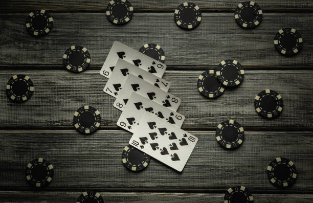 istock A thrilling poker game unfolds on a rustic wooden table, featuring a straight flush combination and various poker chips scattered around, creating a tense atmosphere for the players 2194250533