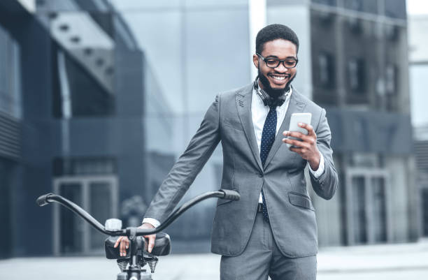 istock Man in Suit Uses Smartphone While Standing Next to Bicycle in Urban Area 2194252757