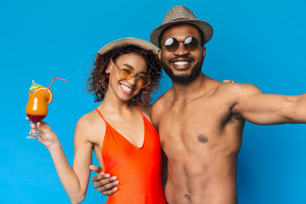 istock Happy Couple Enjoying Summer Fun With Tropical Drinks Against a Bright Blue Backdrop 2194253126