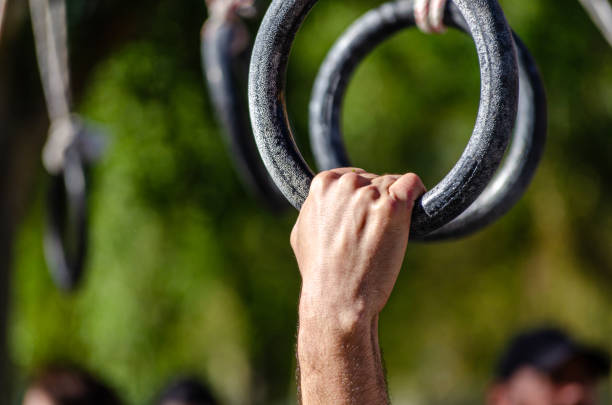 athlete hands grasp a rings at a hanging obstacle in an OCR obstacle course