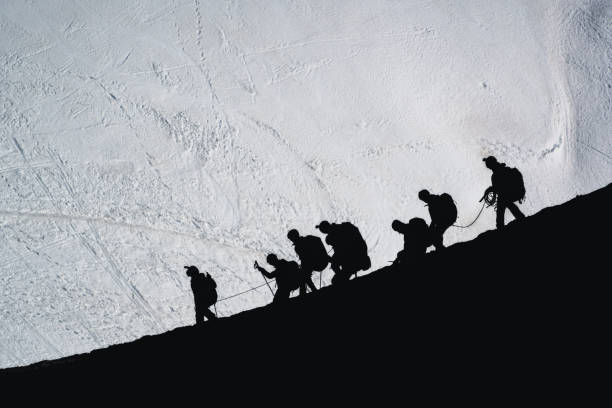 Chamonix-France: November 1, 2024: Paragliders with large backpacks with a parachute inside descend a steep snowy slope from the summit of the Aiguille du Midi to make a parachute jump.