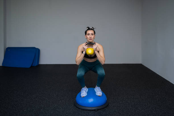 istock Athletic woman performing challenging kettlebell squats on bosu ball, demonstrating core strength, balance, and commitment to fitness training 2194257345