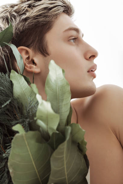 istock Artistic Side Portrait Of Young Man With Greenery Against Bright Background 2194258267