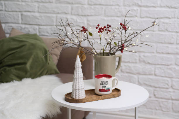 istock Delightful and charming holiday decorations with a festive cup with marshmellows, vase with dry branches and berries in a cozy living room setting. 2194263501