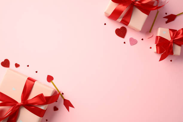 istock Happy Valentine's Day concept. Flat lay composition with pink gift boxes wrapped in red ribbons, surrounded by red and pink heart-shaped decorations and a Cupid's arrow on a pink background 2194264451