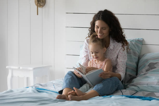 istock Mum and little daughter read book together in bed 2194265010