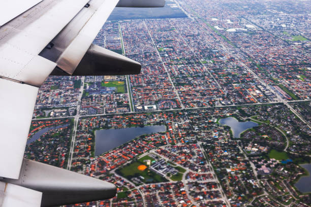 Aerial view of Miami suburbs with airplane wing visible in foreground during flight.