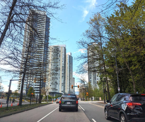 Surrey, Canada - April 30, 2024: Traffic heads north on Whalley Boulevard near Skytrain access. The Whalley neighbourhood undergoes massive redevelopment with thousands of new residential units under construction. Spring afternoon in the downtown district.
