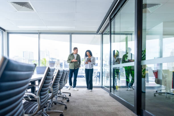 istock Man and woman walking and talking in the office brainstorming or discussing a project. 2194268599