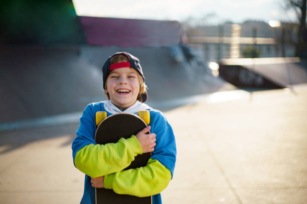 Little dark-haired Latino boy plays in the park with his skateboard wearing a helmet