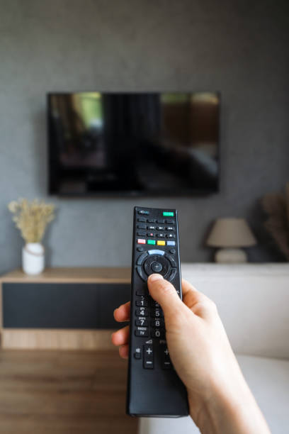 istock Hand holding remote in a modern living room with a television set 2194274392