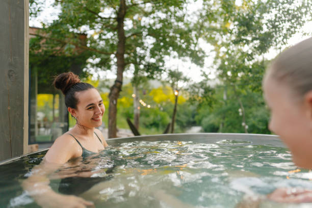 istock Joyful sisterhood: Two sisters laughing together in a hot tub 2194275682