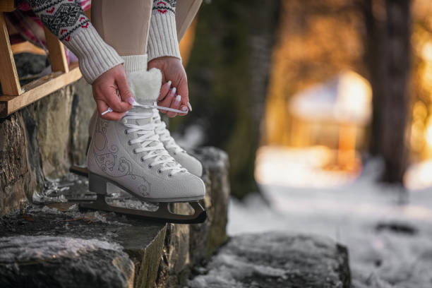 A woman preparing for ice skating, sitting on stairs and tying the ice skates in the snowy forest