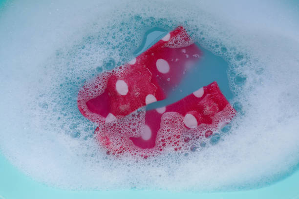 Dirty socks soaked in water, dissolving detergent in blue basin.