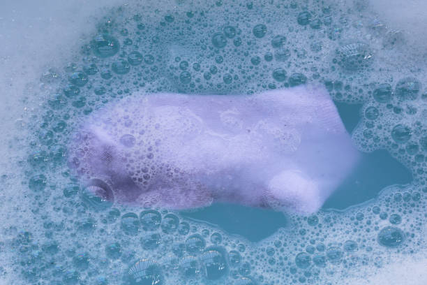 Dirty socks soaked in water, dissolving detergent in blue basin.