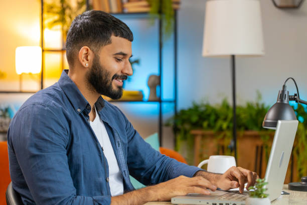 istock Happy Indian man freelancer typing working on laptop writing important email from home office 2194282642