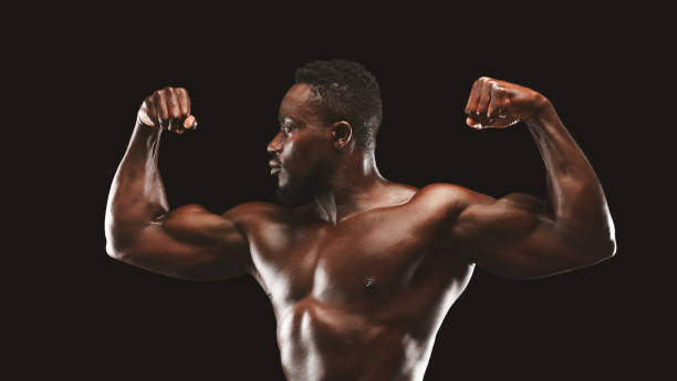 Strong Man Showcasing Muscles in Dramatic Lighting During Fitness Modeling Session