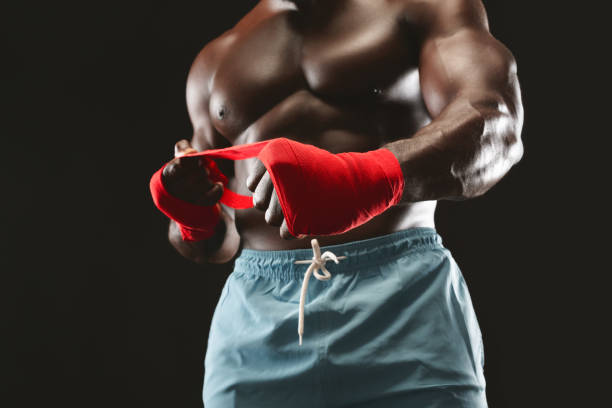 Young Woman Boxer Tying Protective Bandage Around Her Wrists.