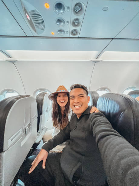 istock Couple Smiling and Taking Selfie on Airplane 2194299321