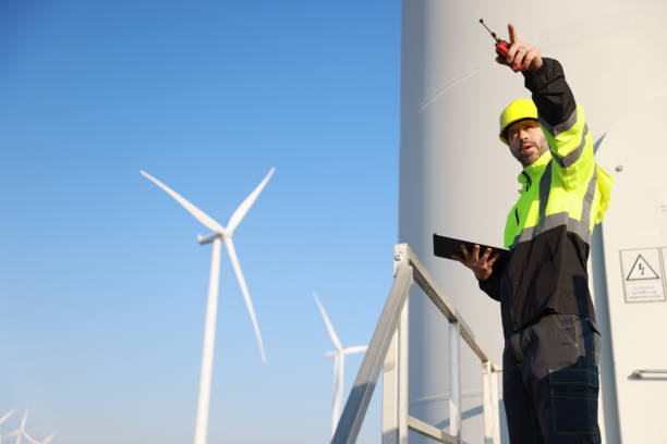 istock A male maintenance technician in uniform uses a talkie and a digital tablet to work on a station wind turbine. Carbon neutrality and clean energy. 2194299922