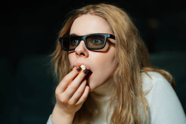 istock Woman enjoying snacks while watching a movie in a dark theater setting 2194300593