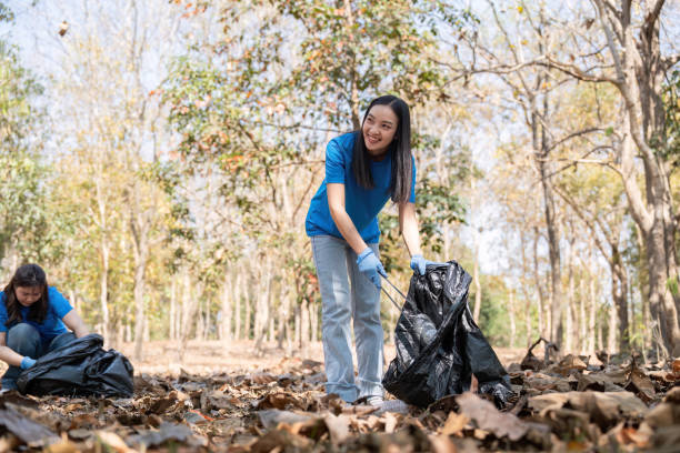 istock Volunteers smiling while collecting garbage in a forest, highlighting community service and environmental care 2194300611