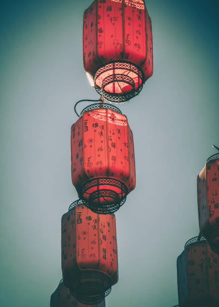 Crimson lanterns hang against a muted sky, their intricate patterns hinting at a rich cultural heritage.  The aged fabric and metal frames evoke a sense of history and tradition.