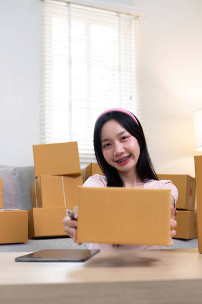 istock Young female entrepreneur showcasing a package while managing her e-commerce business from home 2194303306